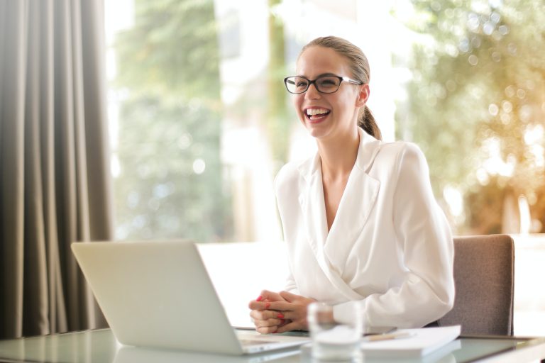 young lady wearing white in an office smiling